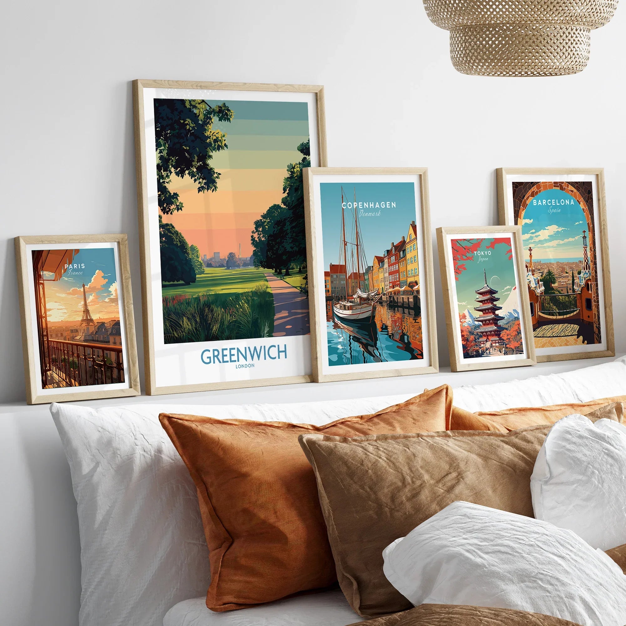 Five framed travel art prints of Paris, Greenwich, Copenhagen, Tokyo, and Barcelona above a bed