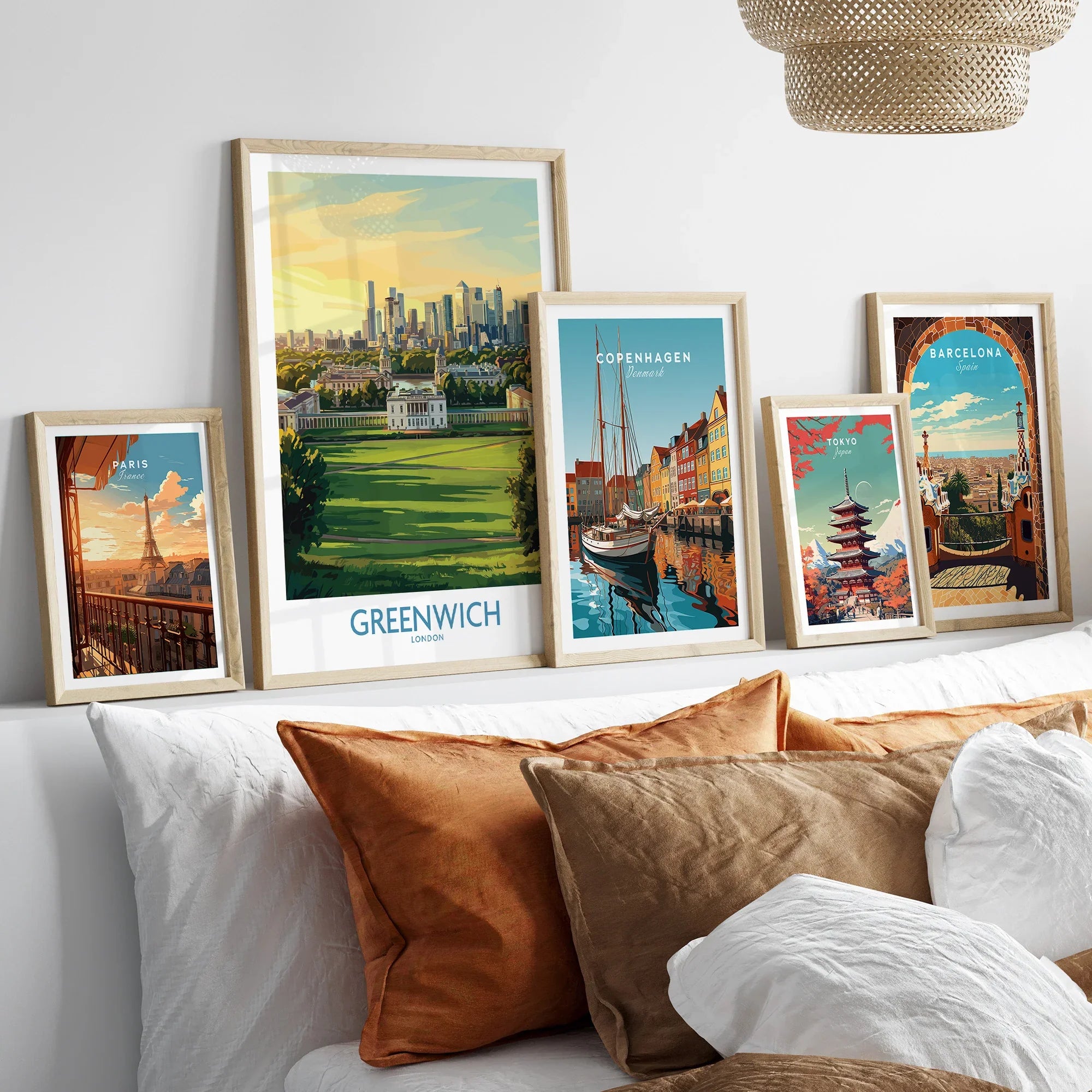 Framed travel art prints of Paris, Greenwich, Copenhagen, Tokyo, and Barcelona above a bed.