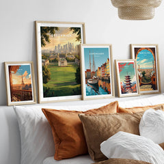 Framed travel posters of Greenwich, Paris, Copenhagen, Tokyo, and Barcelona above a modern bed.