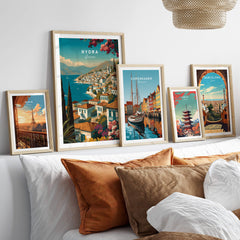 Hydra Greece Wall Art Print | Mediterranean Coastal Town Travel Poster displayed among other travel posters on a cozy sofa.