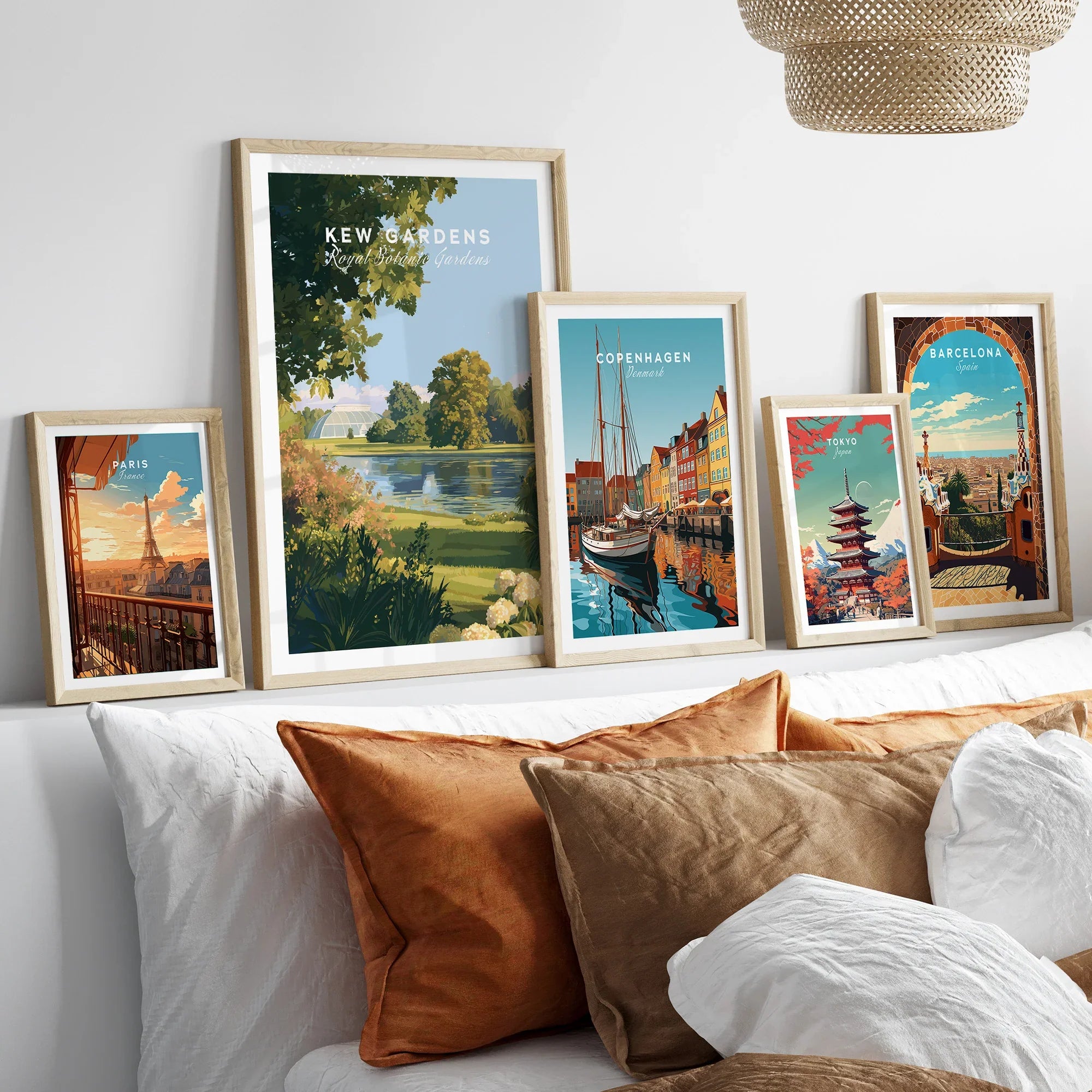 Framed travel posters of Kew Gardens, Copenhagen, Paris, Tokyo and Barcelona above a bed