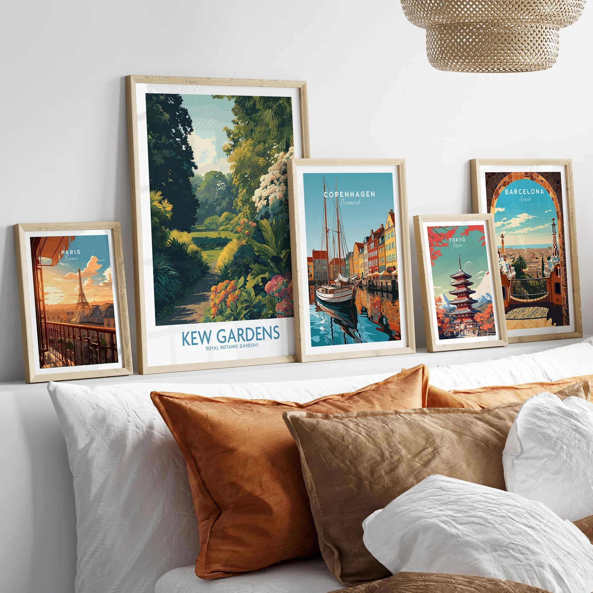 Set of five framed travel posters above bed with pillows, natural wood frames.