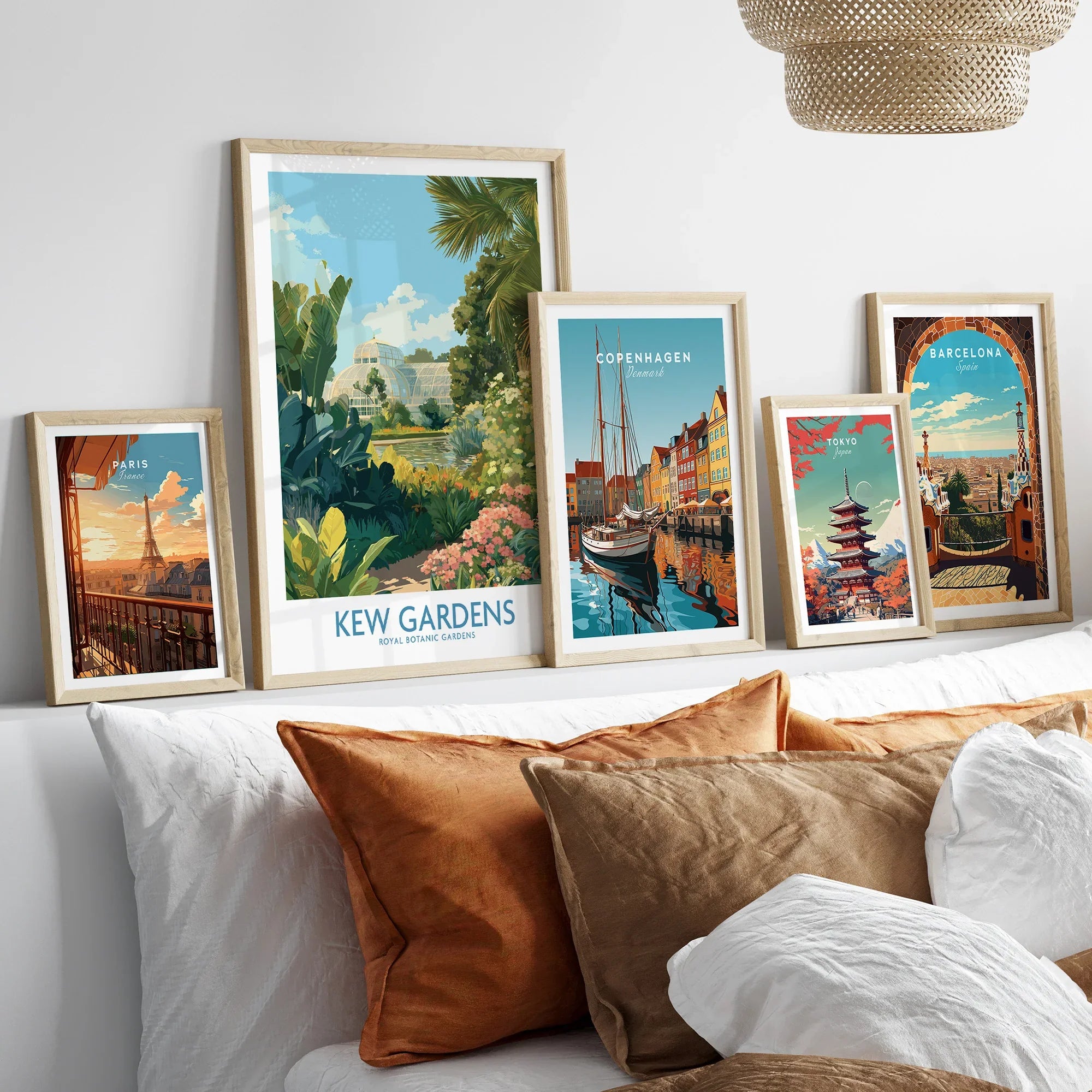 Framed travel art prints of Kew Gardens, Paris, Copenhagen, Tokyo, and Barcelona above a bed