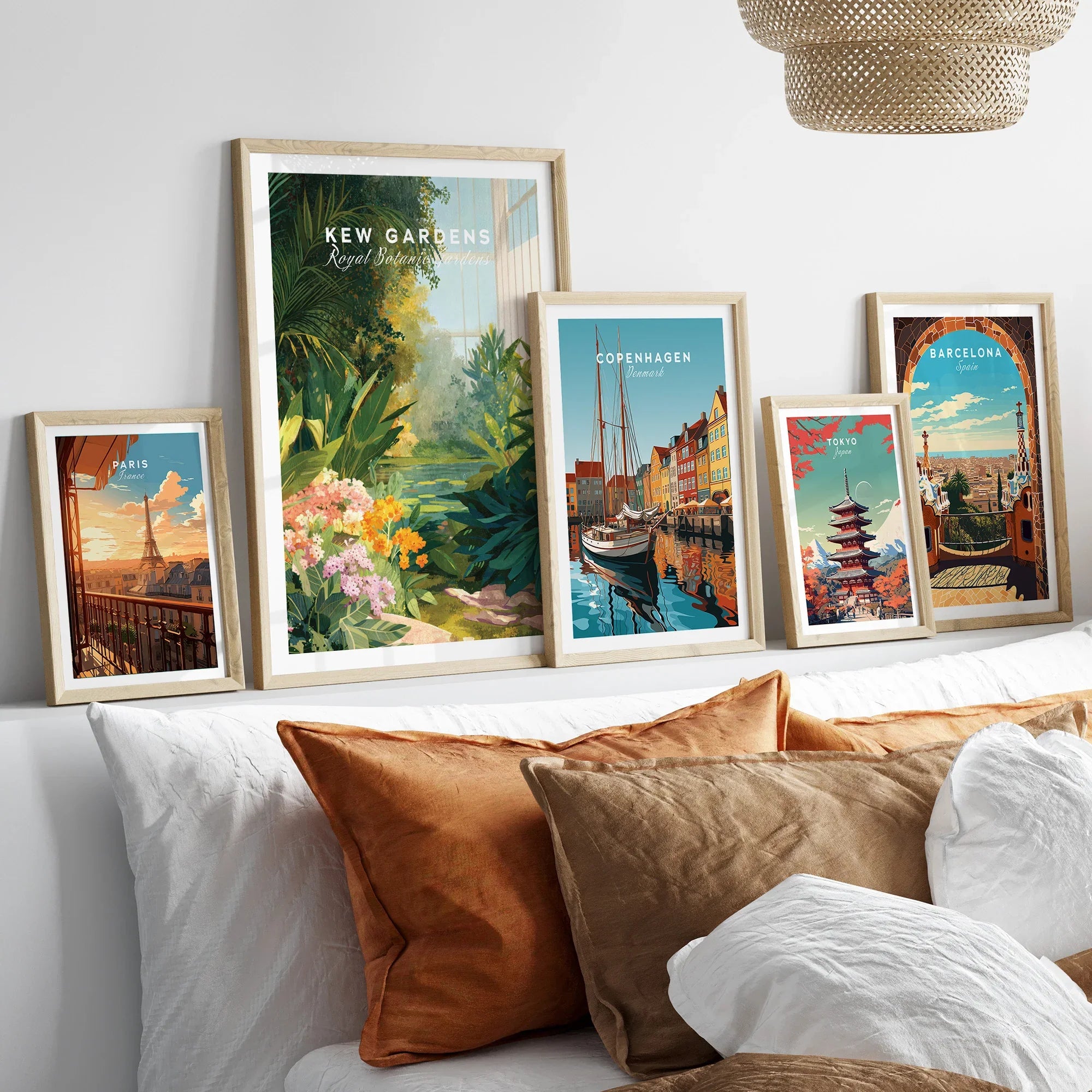 Framed travel art prints of Kew Gardens, Paris, Copenhagen, Tokyo, Barcelona above a bed