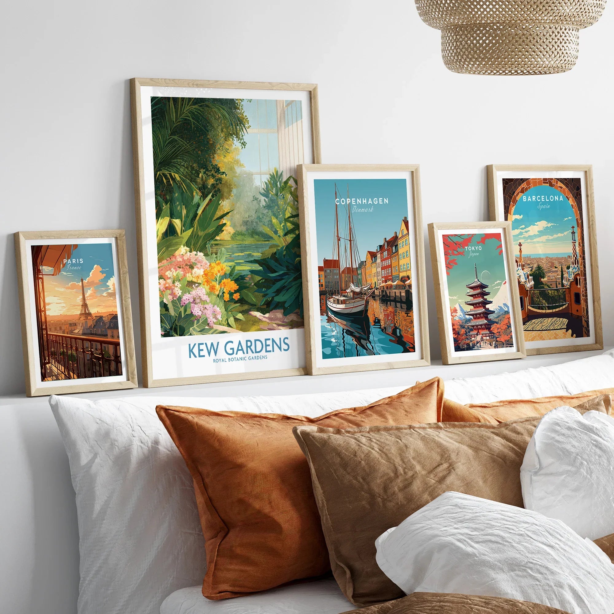Set of five framed travel art prints above bed, featuring Paris, Kew Gardens, Copenhagen, Tokyo, Barcelona.