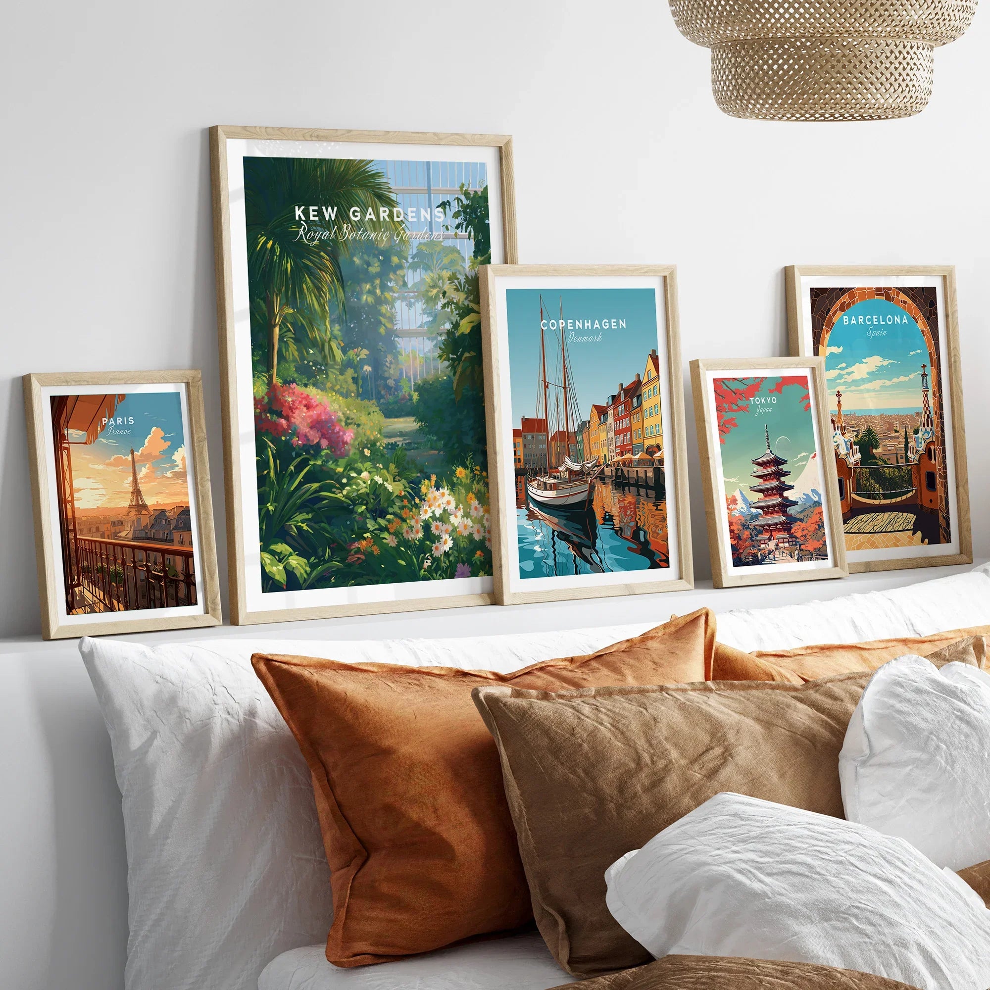 Framed travel art prints of Kew Gardens, Paris, Copenhagen, Tokyo, and Barcelona above a bed.