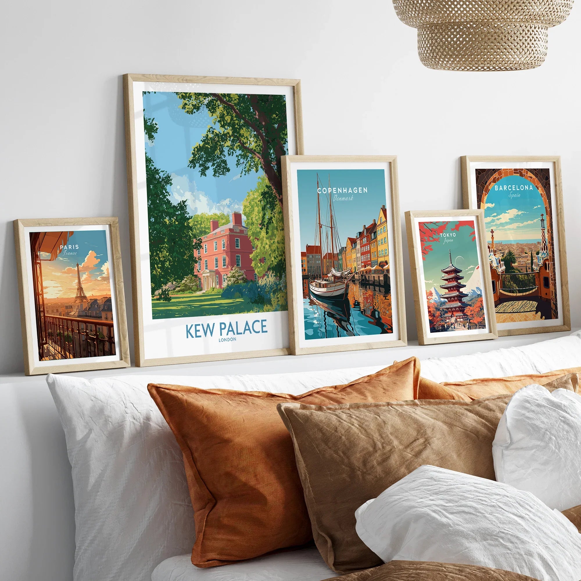 Framed travel posters of Kew Palace, Copenhagen, Paris, Tokyo, and Barcelona above a bed