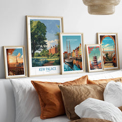 Framed travel posters of Kew Palace, Paris, Copenhagen, Tokyo, and Barcelona above a bed.