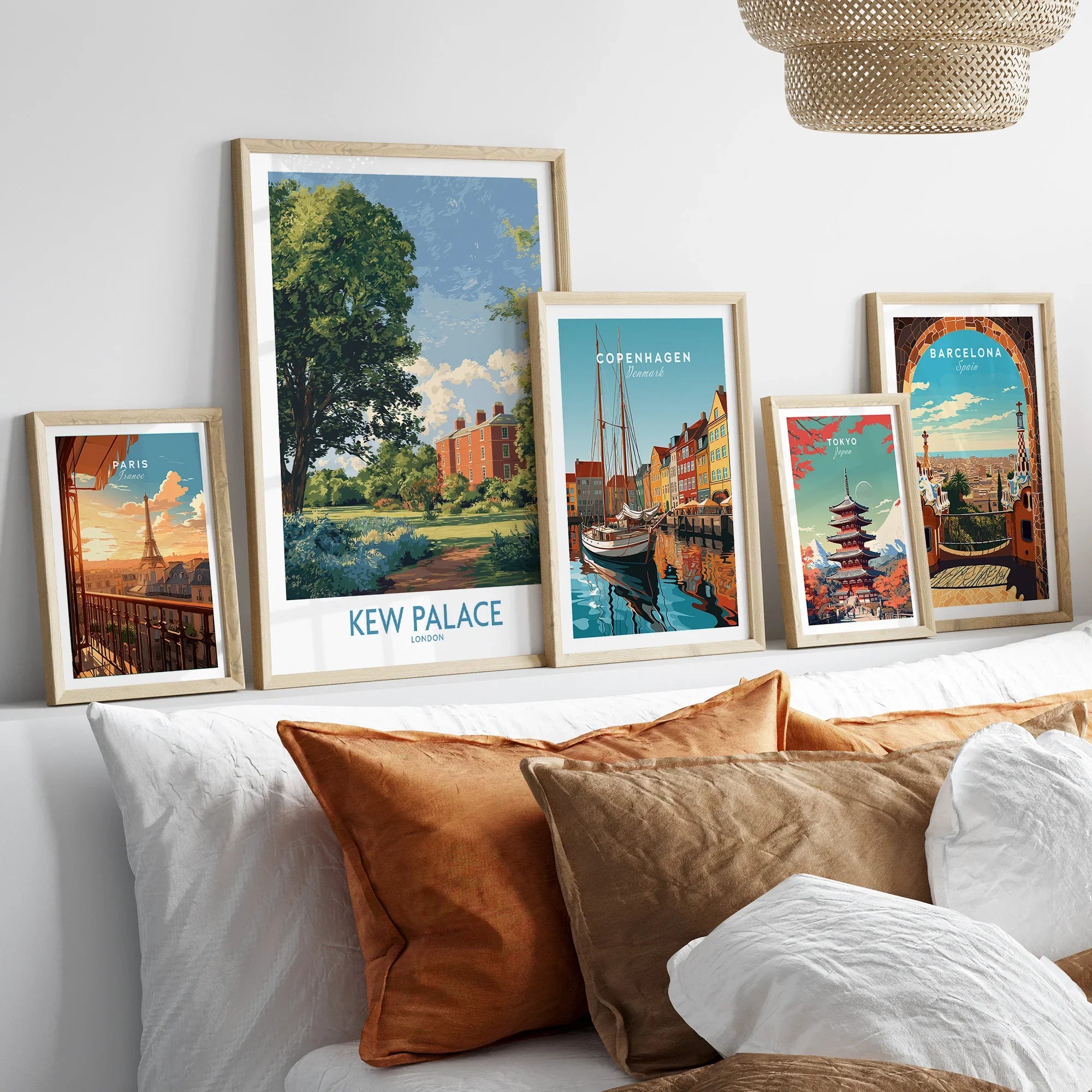 Framed travel posters of Kew Palace, Paris, Copenhagen, Tokyo, and Barcelona above a bed.