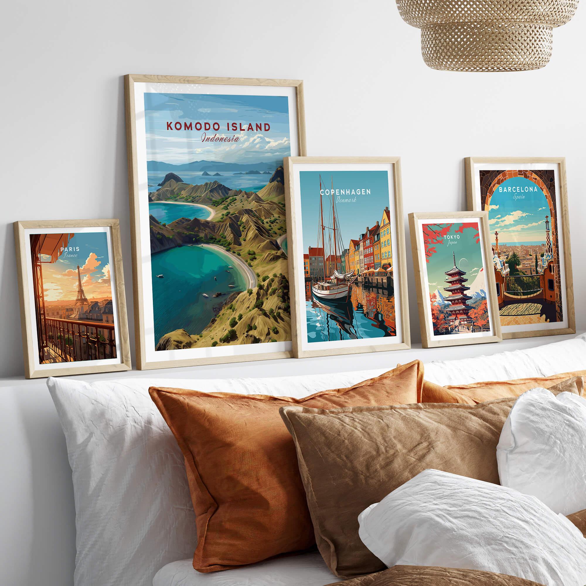 Five framed travel posters above a bed, featuring Paris, Komodo Island, Copenhagen, Tokyo, and Barcelona.