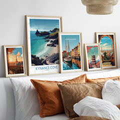 Kynance Cove Cornwall Poster | Scenic Sea Cliffs & Beach Canvas Print displayed among other travel posters on a cozy sofa.