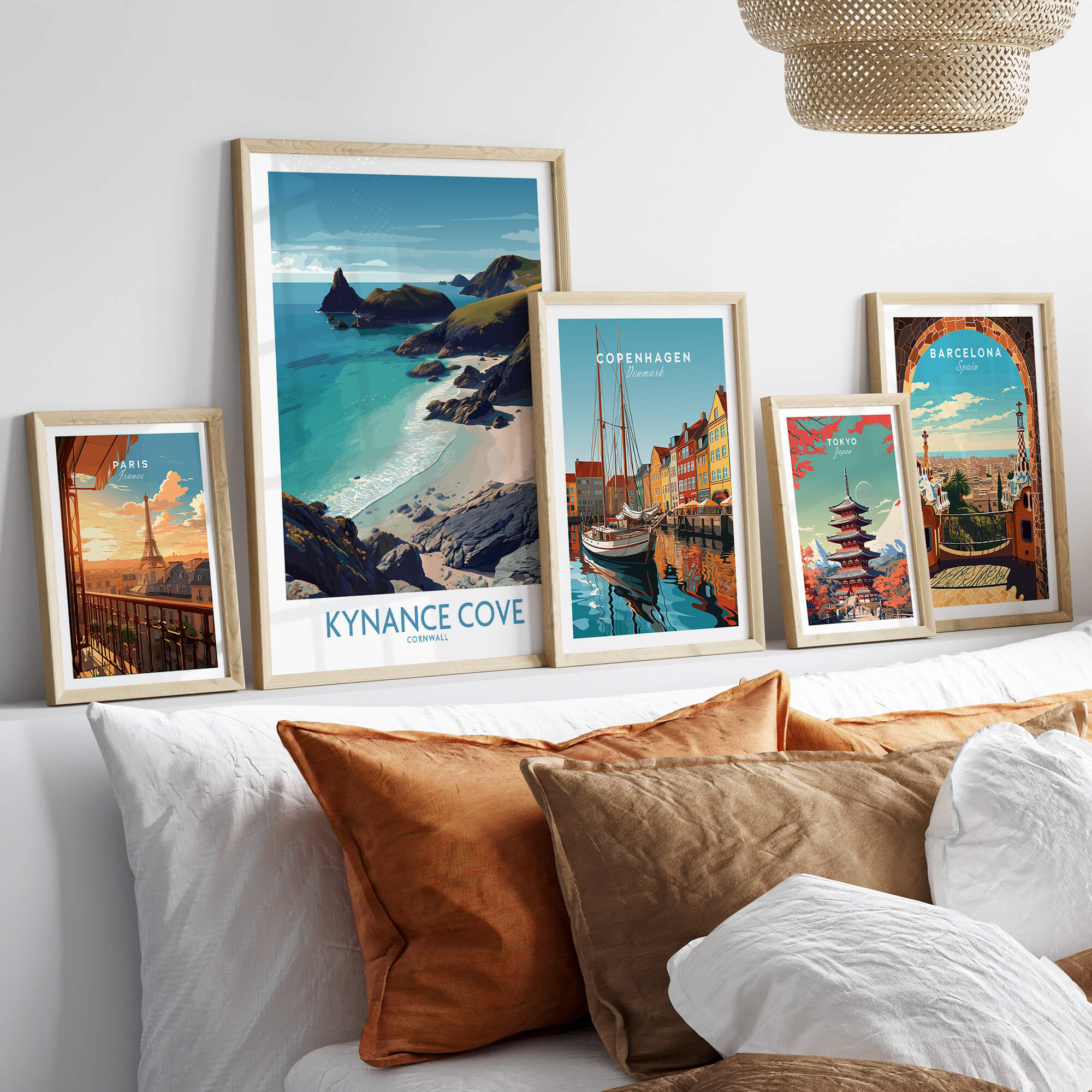 Kynance Cove Cornwall Poster | Scenic Sea Cliffs & Beach Canvas Print displayed among other travel posters on a cozy sofa.