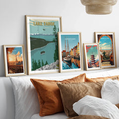 Framed travel posters of Lake Tahoe, Paris, Copenhagen, Tokyo, and Barcelona above a bed