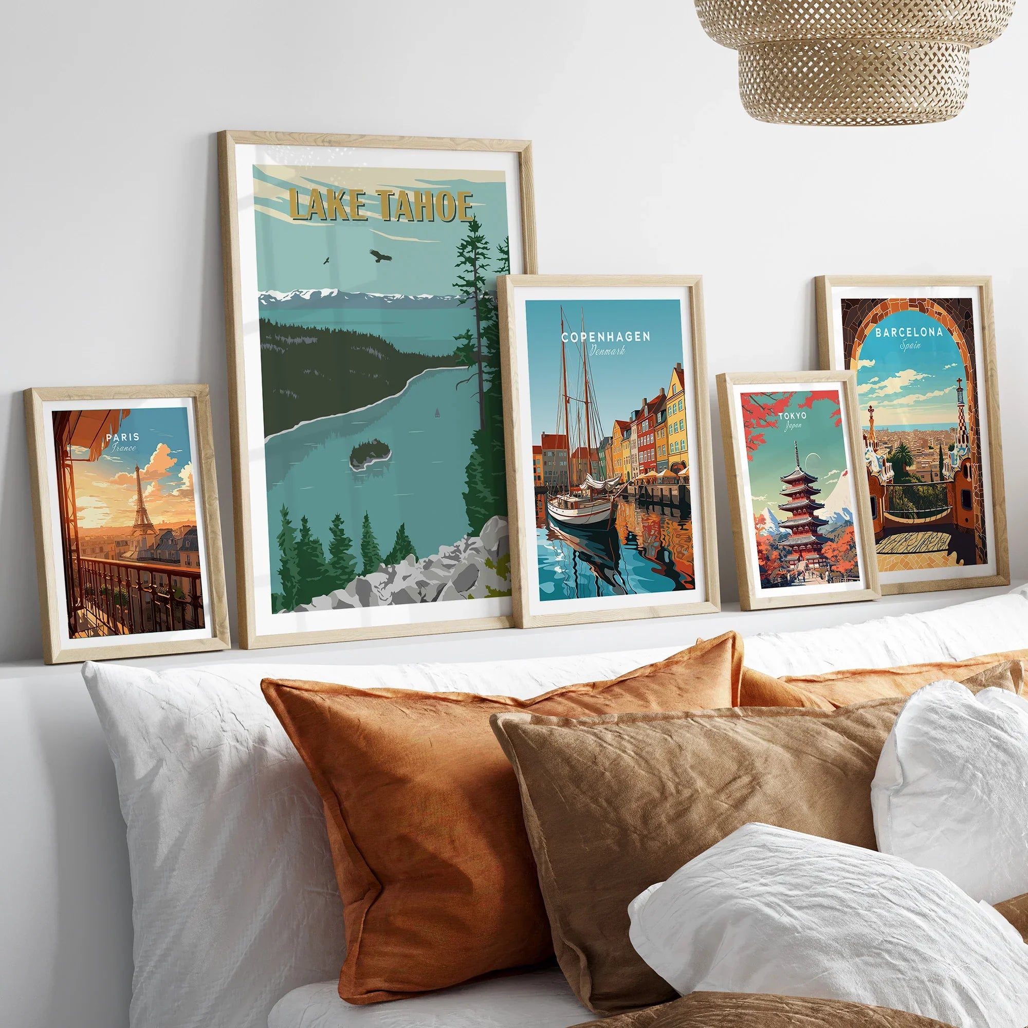 Framed travel posters of Lake Tahoe, Paris, Copenhagen, Tokyo, and Barcelona above a bed