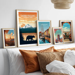 Framed travel posters of Paris, Lassen National Park, Copenhagen, Tokyo, and Barcelona above a bed