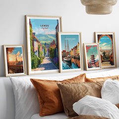 Set of five framed travel posters above a bed, featuring Paris, Lewes, Copenhagen, Tokyo, and Barcelona.