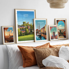 Framed travel posters of Lewes, Paris, Copenhagen, Tokyo, and Barcelona above a bed.