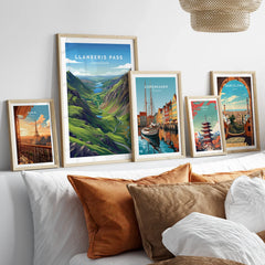 Set of five framed travel art prints above bed, featuring iconic city skylines and landscapes.