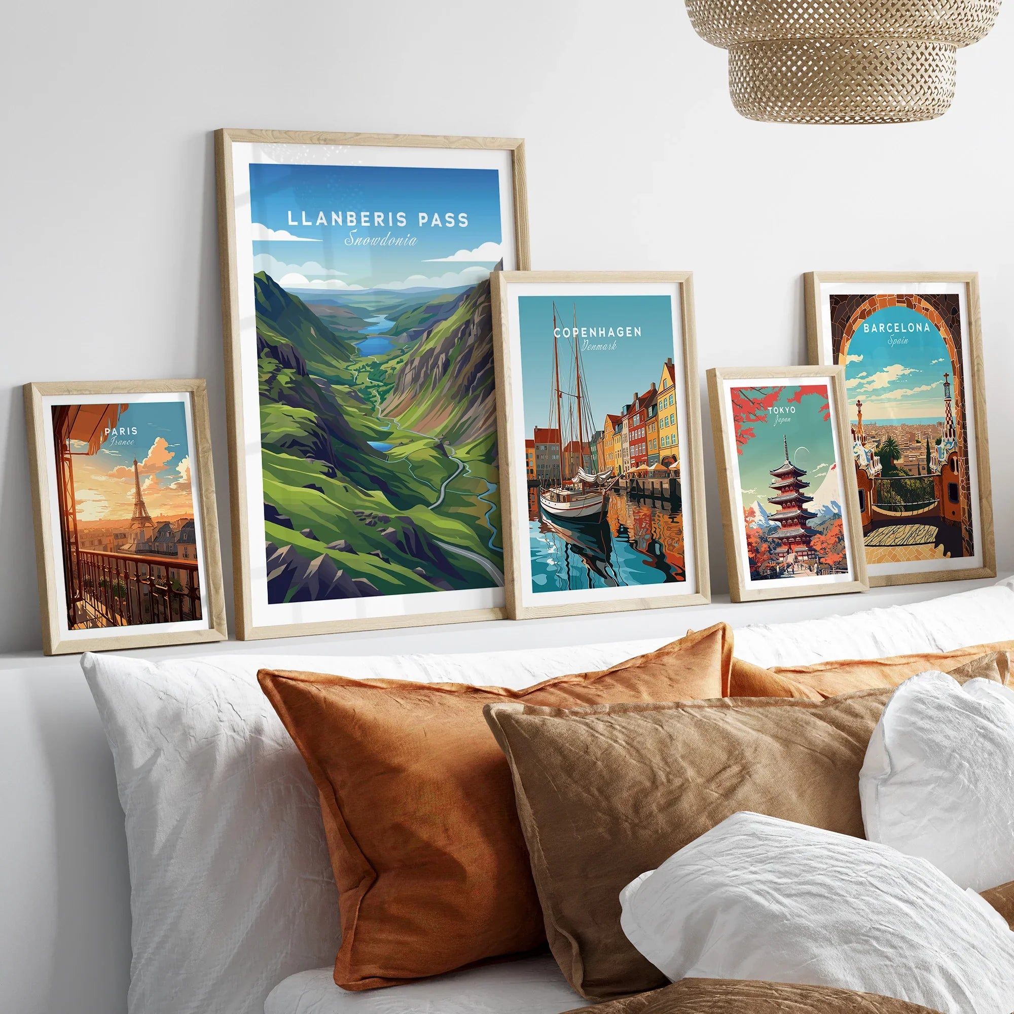 Set of five framed travel art prints above bed, featuring iconic city skylines and landscapes.