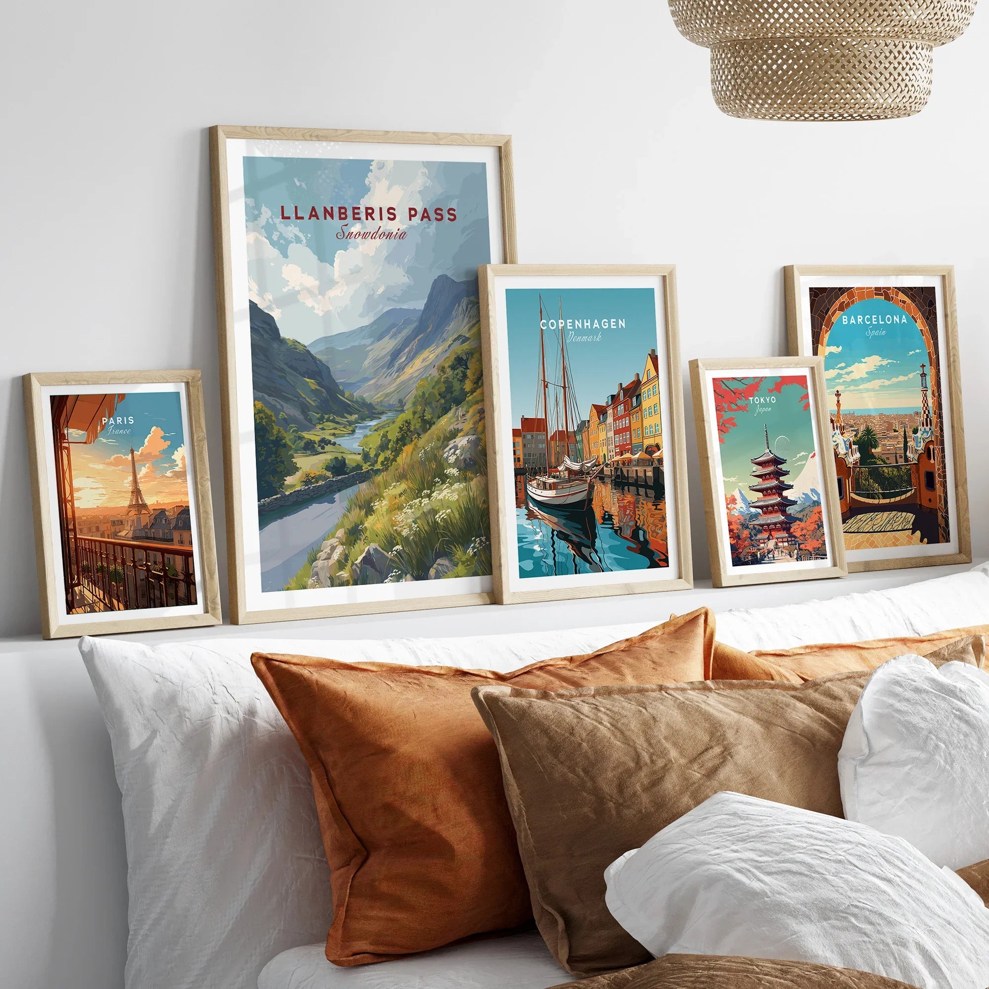 Set of five framed travel posters above a bed, featuring scenic city and nature wall art.