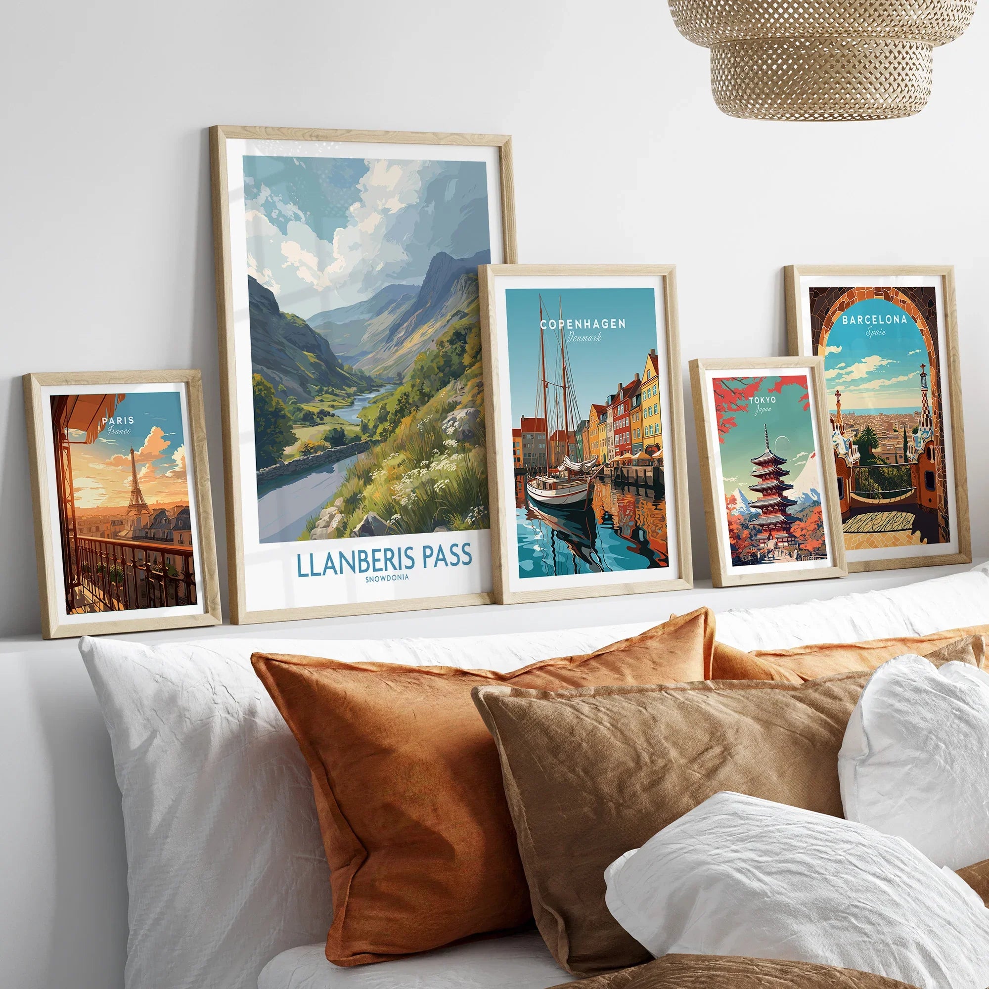 Framed travel posters of Llanberis Pass, Paris, Copenhagen, Tokyo and Barcelona above a bed
