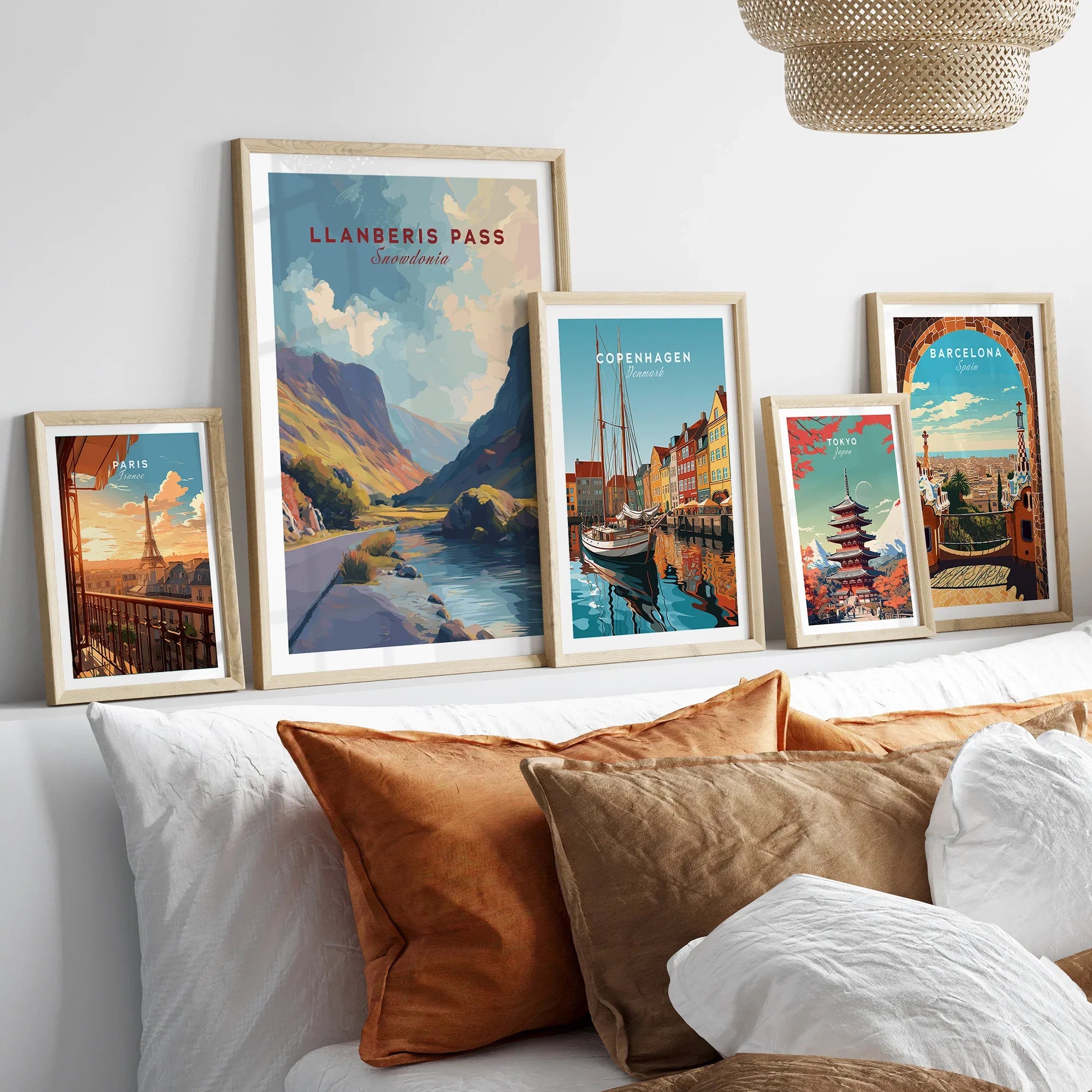 Framed travel posters of Llanberis Pass, Paris, Copenhagen, Tokyo, Barcelona above a bed