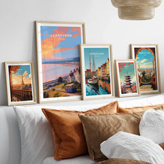 Set of five framed travel art prints above a bed, featuring Paris, Llandudno, Copenhagen, Tokyo, and Barcelona.