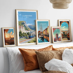 Travel art prints of city skylines and landmarks in natural wood frames above bed