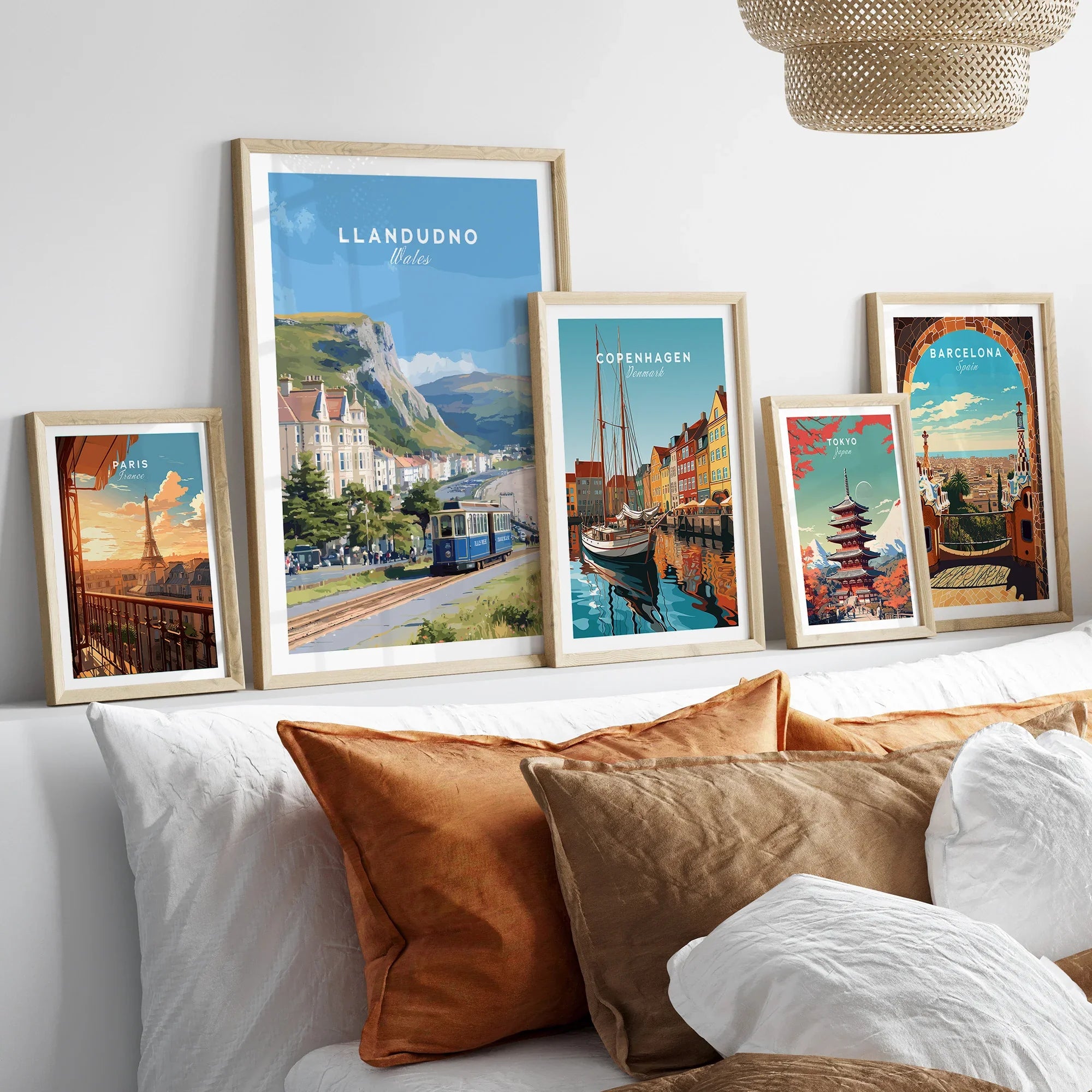 Travel art prints of city skylines and landmarks in natural wood frames above bed