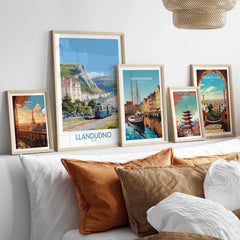Set of five framed travel posters above bed, featuring Paris, Llandudno, Copenhagen, Tokyo, and Barcelona.