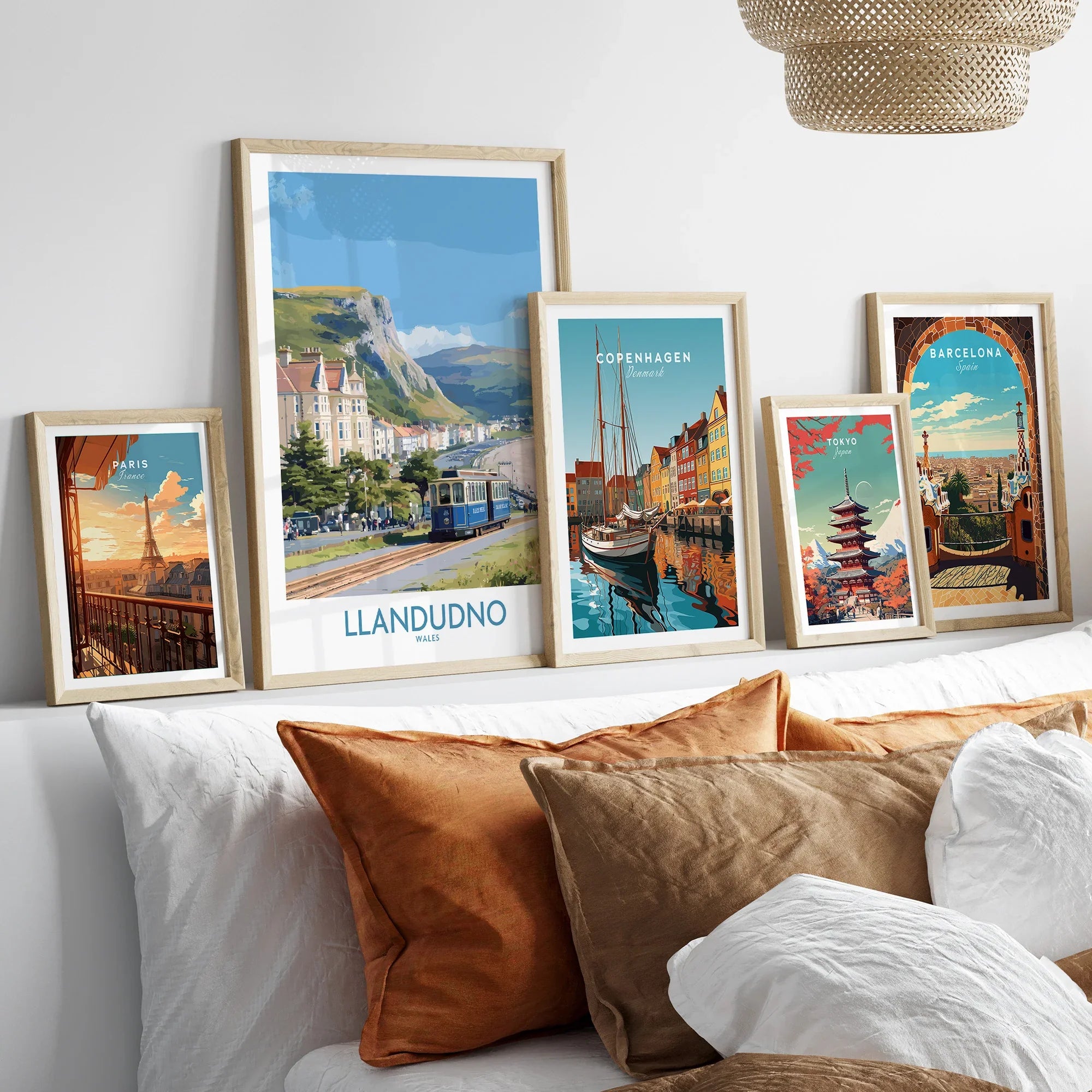 Set of five framed travel posters above bed, featuring Paris, Llandudno, Copenhagen, Tokyo, and Barcelona.