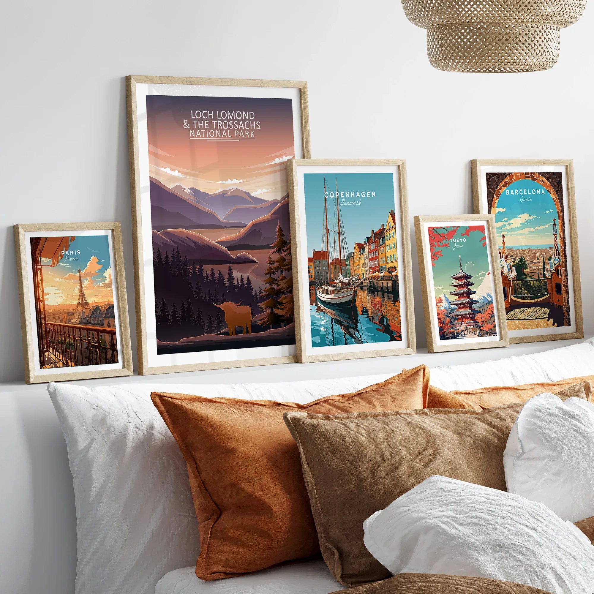Set of five framed travel art prints above bed, featuring Paris, Loch Lomond, Copenhagen, Tokyo, Barcelona.