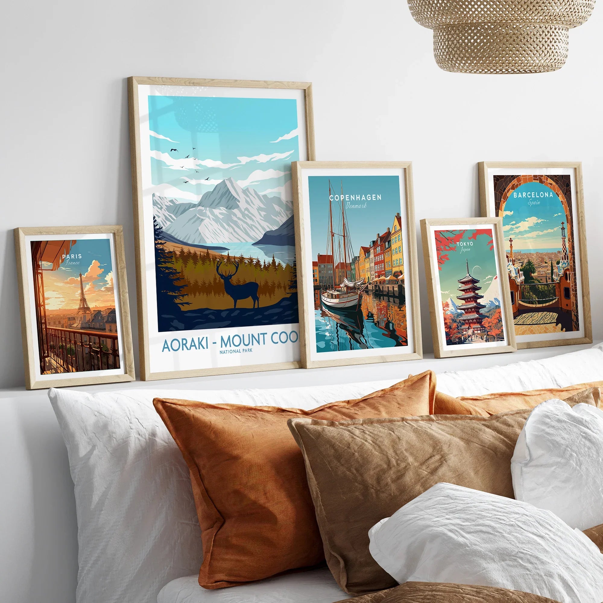 Set of five framed travel posters above bed, featuring Paris, Aoraki, Copenhagen, Tokyo, Barcelona.