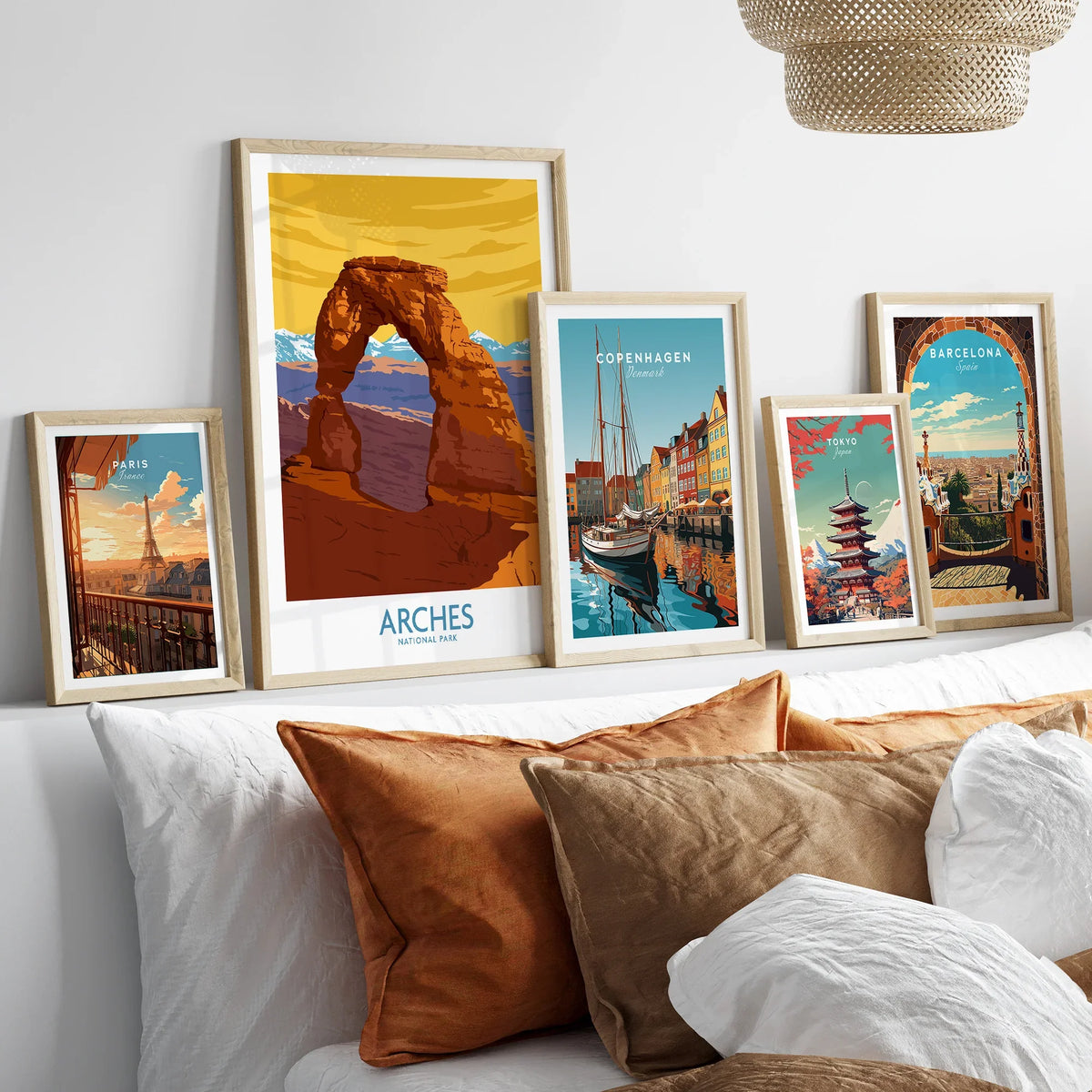 Framed travel posters of Paris, Arches National Park, Copenhagen, Tokyo, and Barcelona above bed