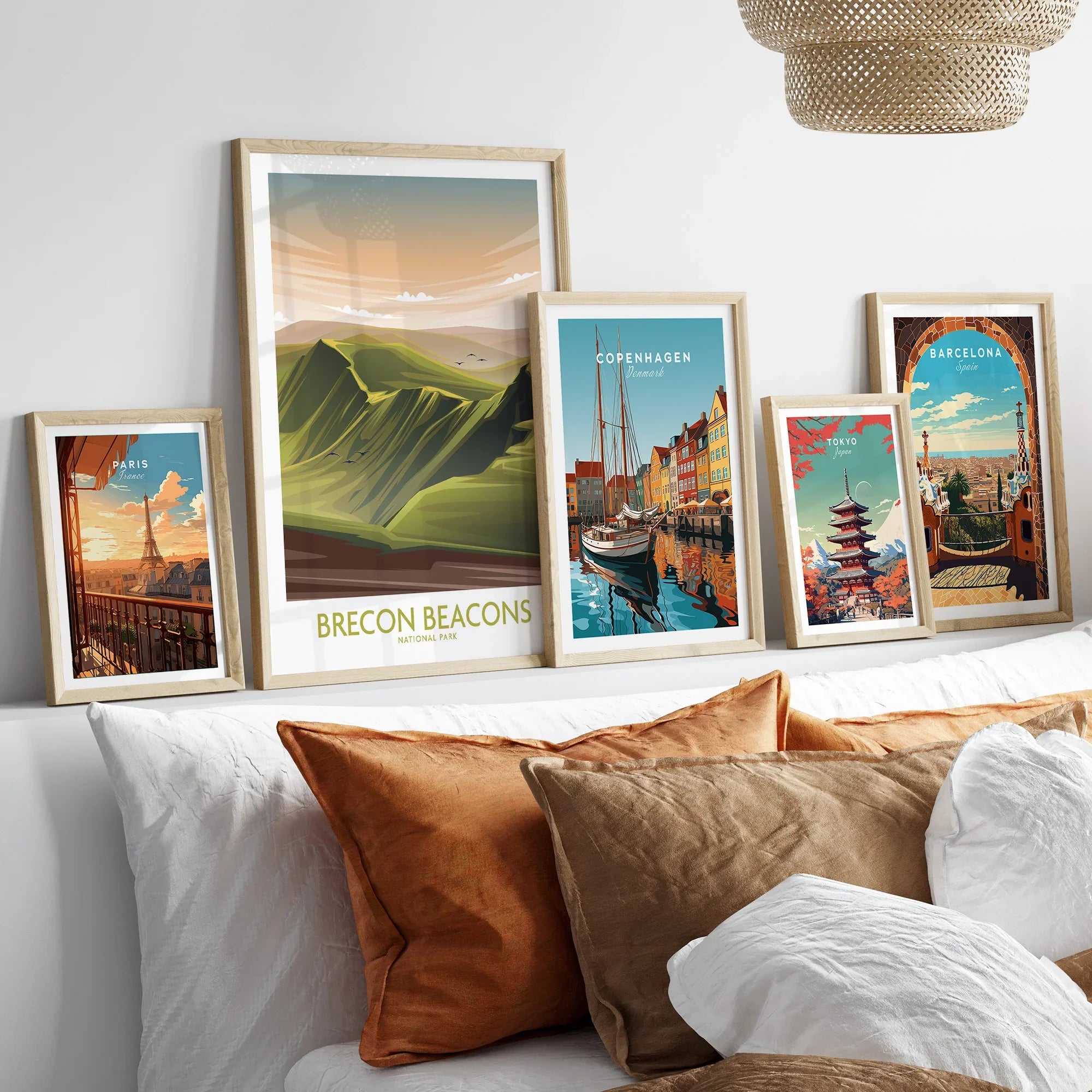 Framed travel posters of Paris, Brecon Beacons, Copenhagen, Tokyo, and Barcelona art above a bed