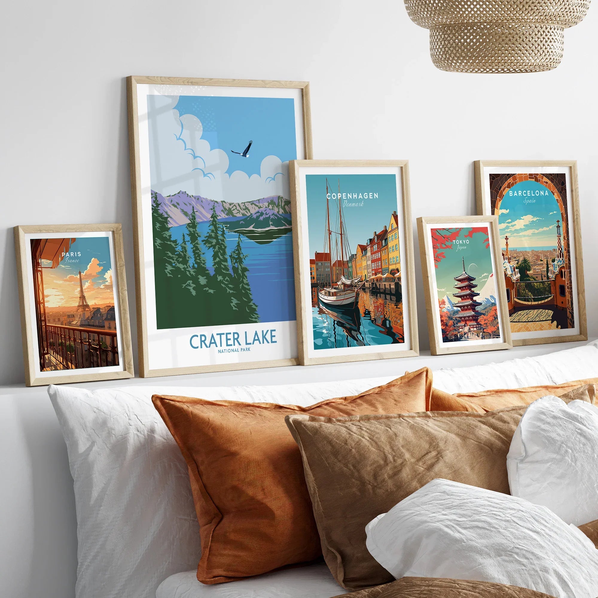Set of five framed travel art prints above bed, featuring Paris, Crater Lake, Copenhagen, Tokyo, Barcelona.