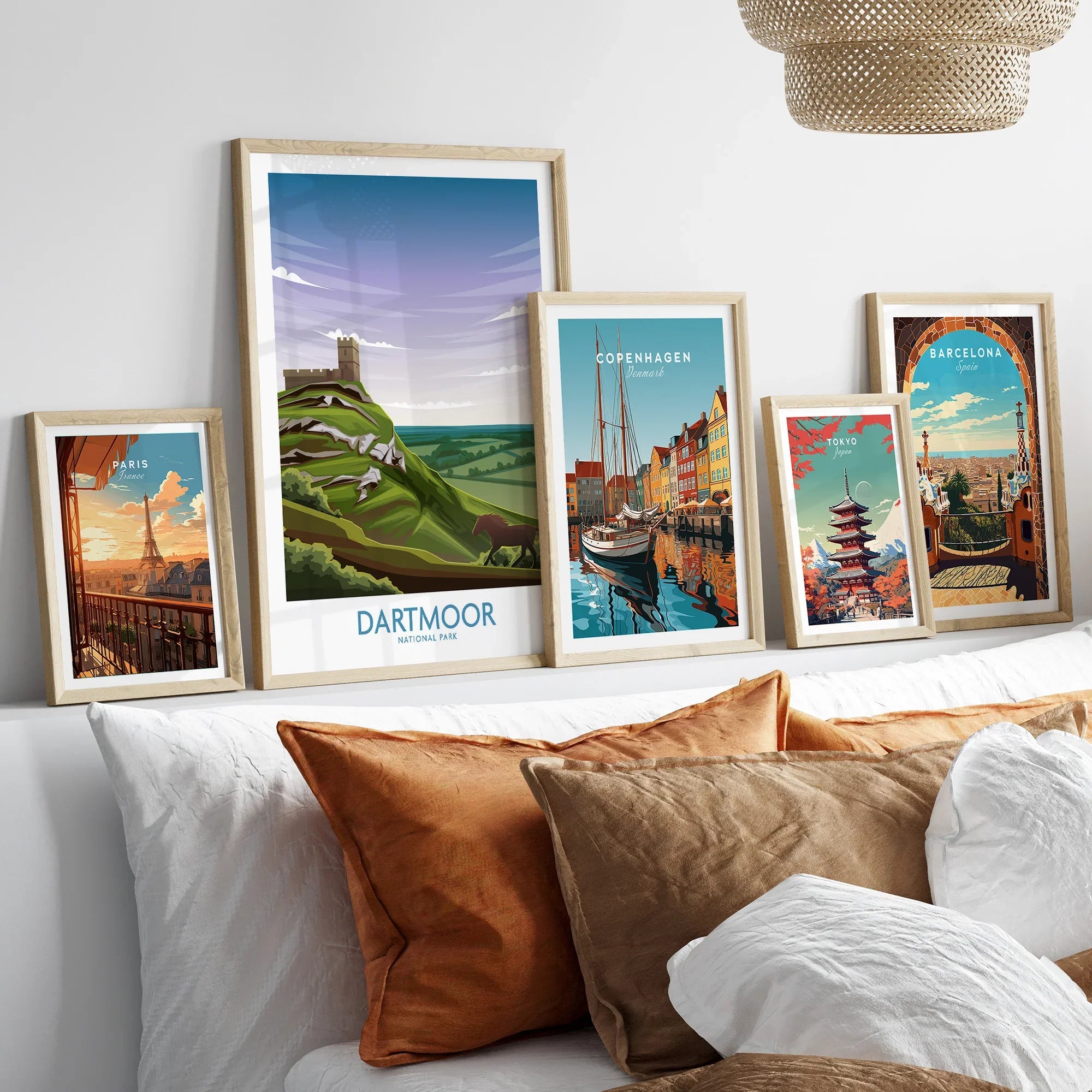 Set of five framed travel posters above bed, featuring Paris, Dartmoor National Park, Copenhagen, Tokyo, Barcelona.