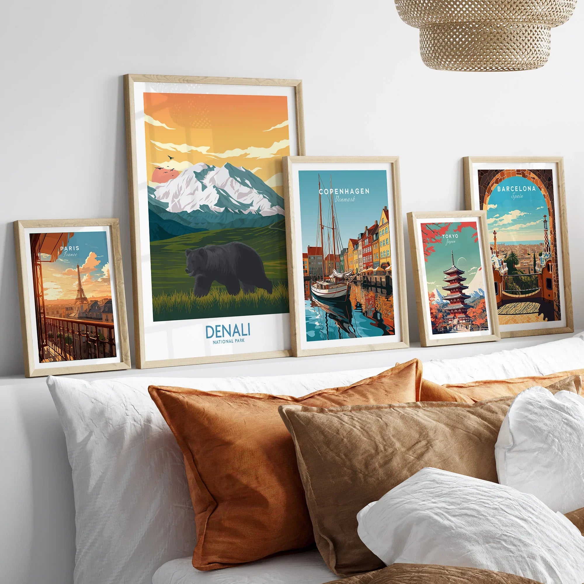 Framed travel art prints of Paris, Denali, Copenhagen, Tokyo, and Barcelona above a bed