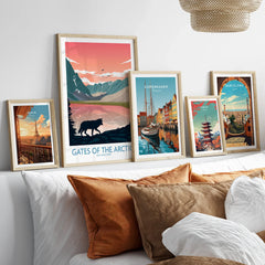 Set of five framed travel art prints above a bed, featuring Paris, Arctic National Park, Copenhagen, Tokyo, and Barcelona scenes.