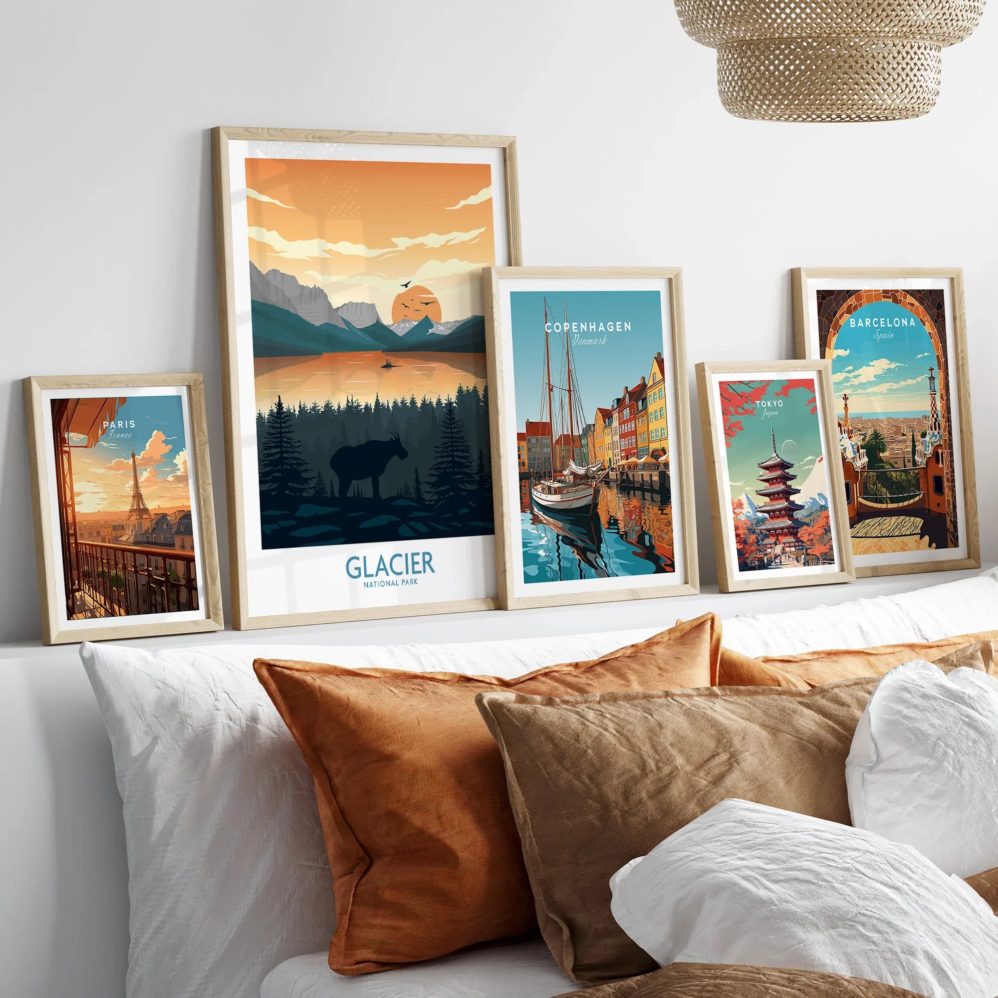 Five framed travel art prints above a bed, featuring Paris, Glacier National Park, Copenhagen, Tokyo, and Barcelona scenes.