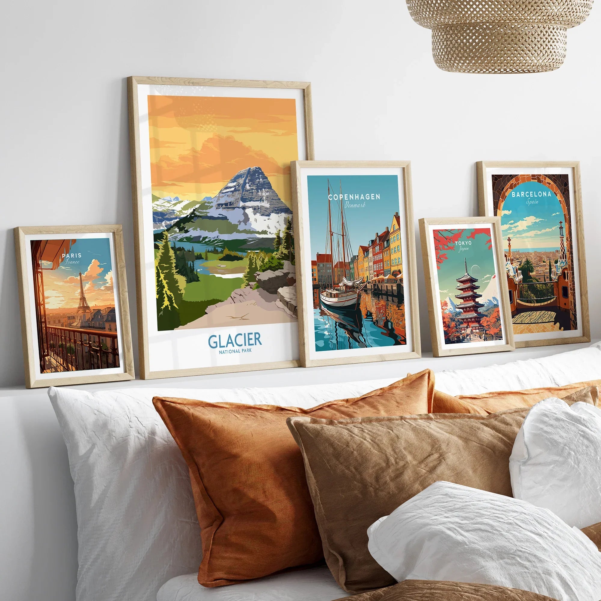 Five framed travel art prints of Paris, Glacier National Park, Copenhagen, Tokyo, and Barcelona above a bed