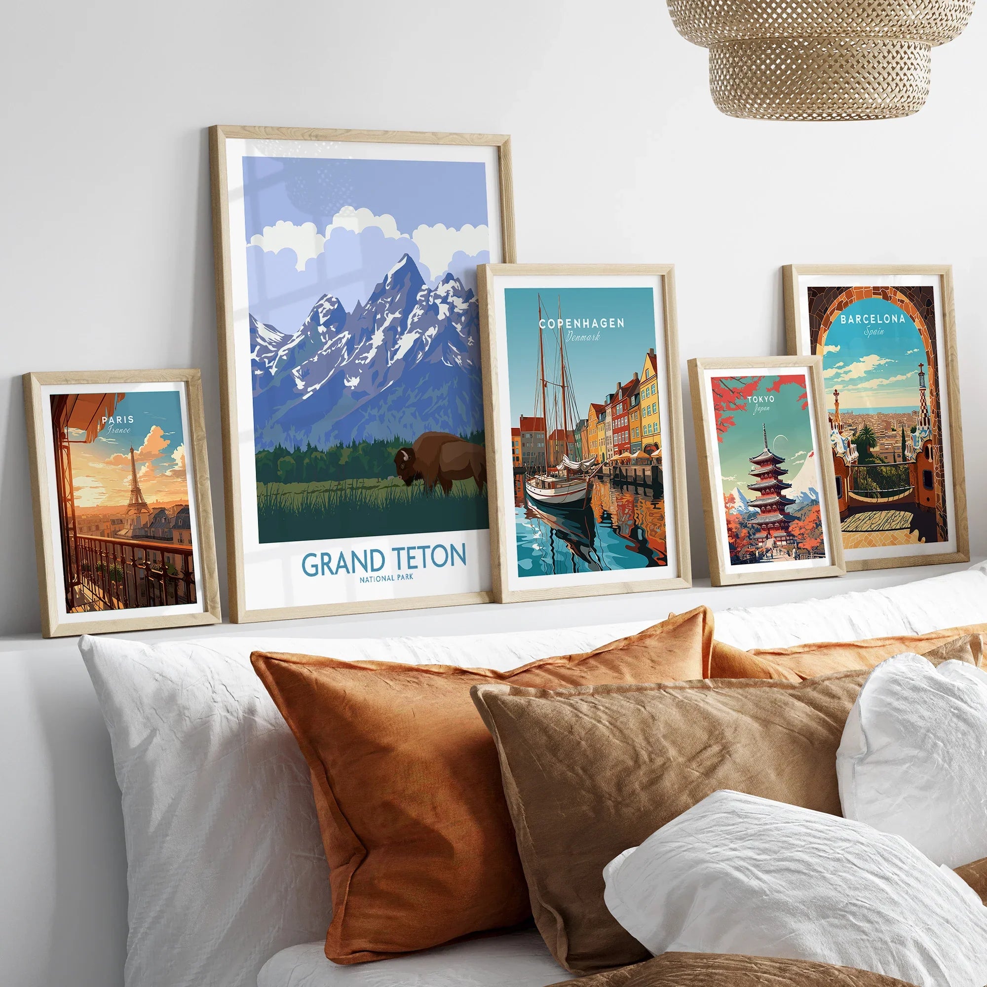 Framed travel art prints of Paris, Grand Teton, Copenhagen, Tokyo, and Barcelona above a bed