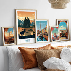 Five framed travel and city skyline posters above a bed with white and brown pillows