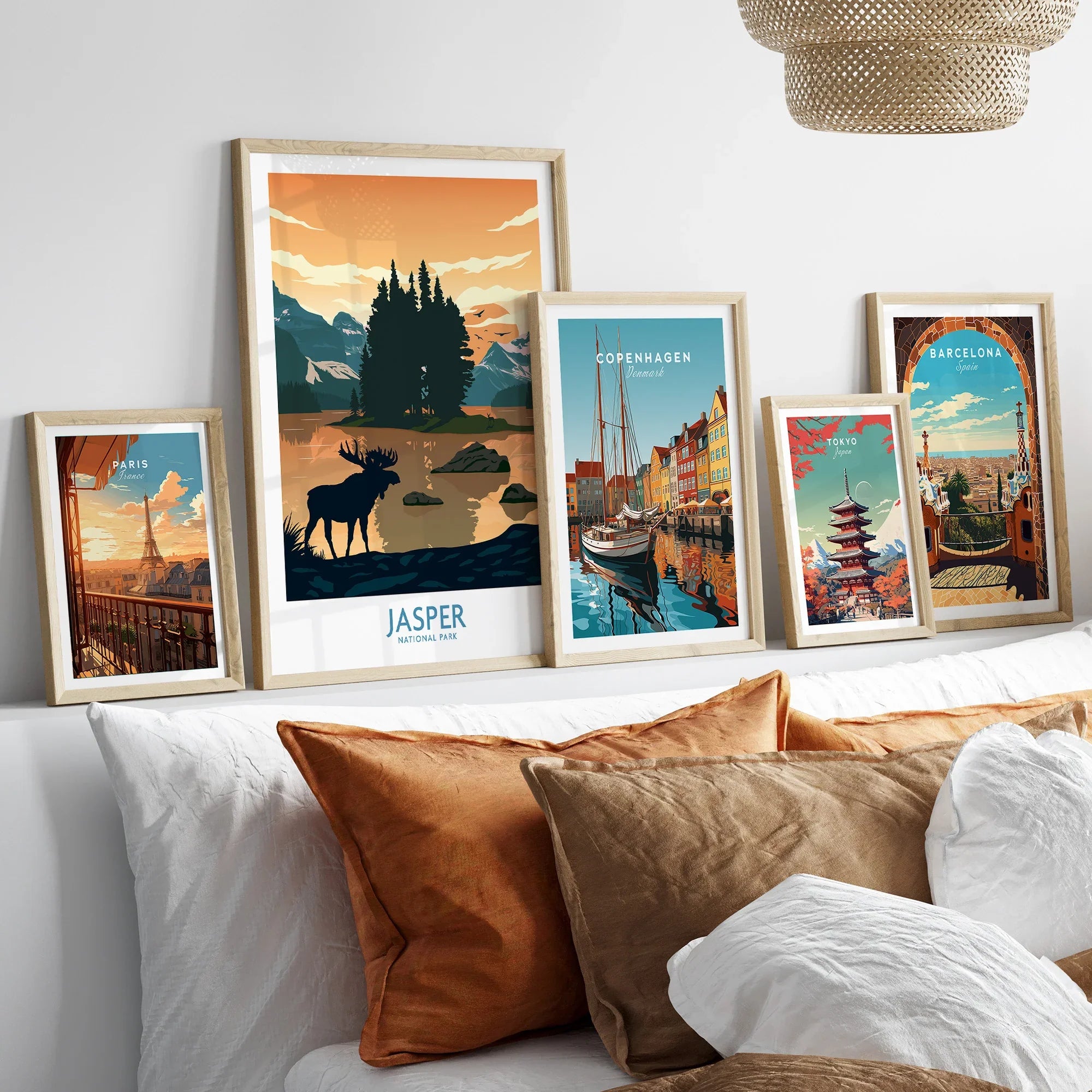 Five framed travel and city skyline posters above a bed with white and brown pillows