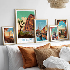 Set of five framed travel art prints above bed, featuring Joshua Tree, Paris, Copenhagen, Tokyo, Barcelona.
