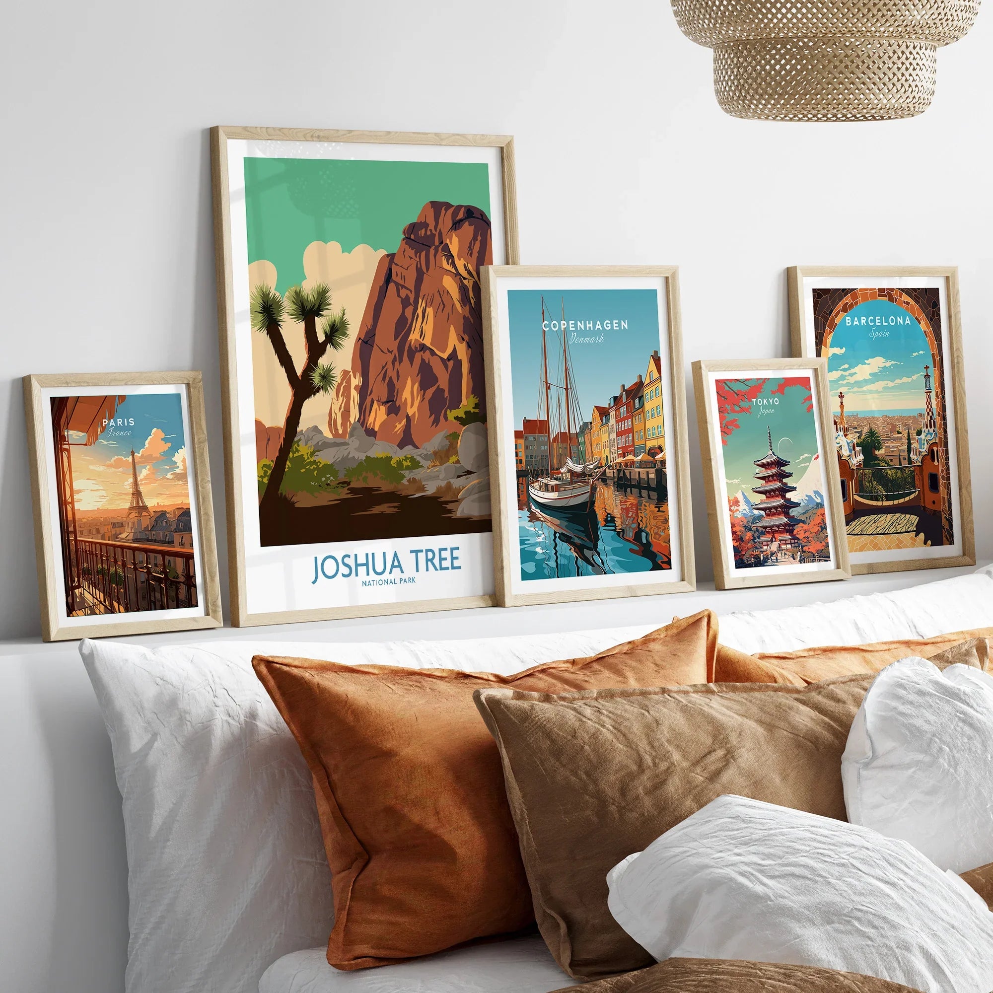 Set of five framed travel art prints above bed, featuring Joshua Tree, Paris, Copenhagen, Tokyo, Barcelona.