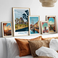 Set of five framed travel posters above a bed, featuring city skylines and national parks.
