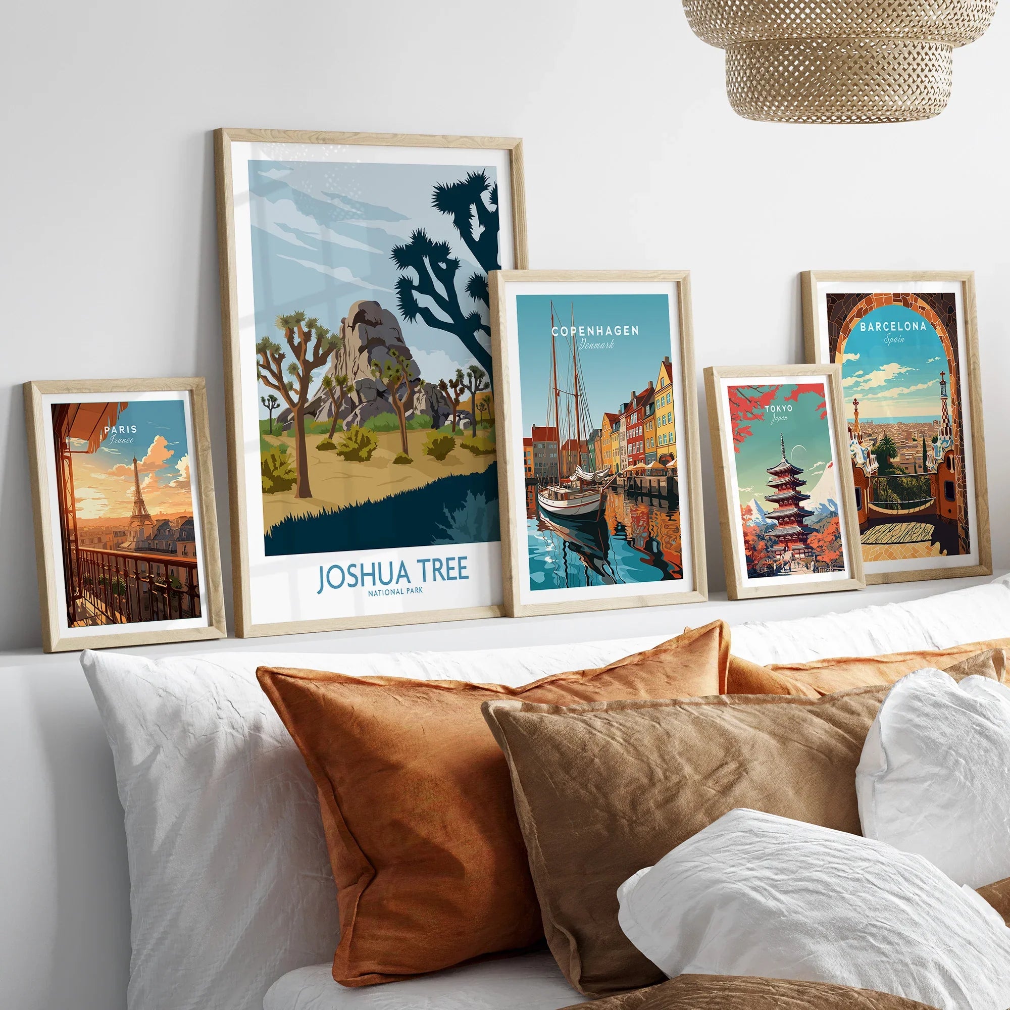 Set of five framed travel posters above a bed, featuring city skylines and national parks.