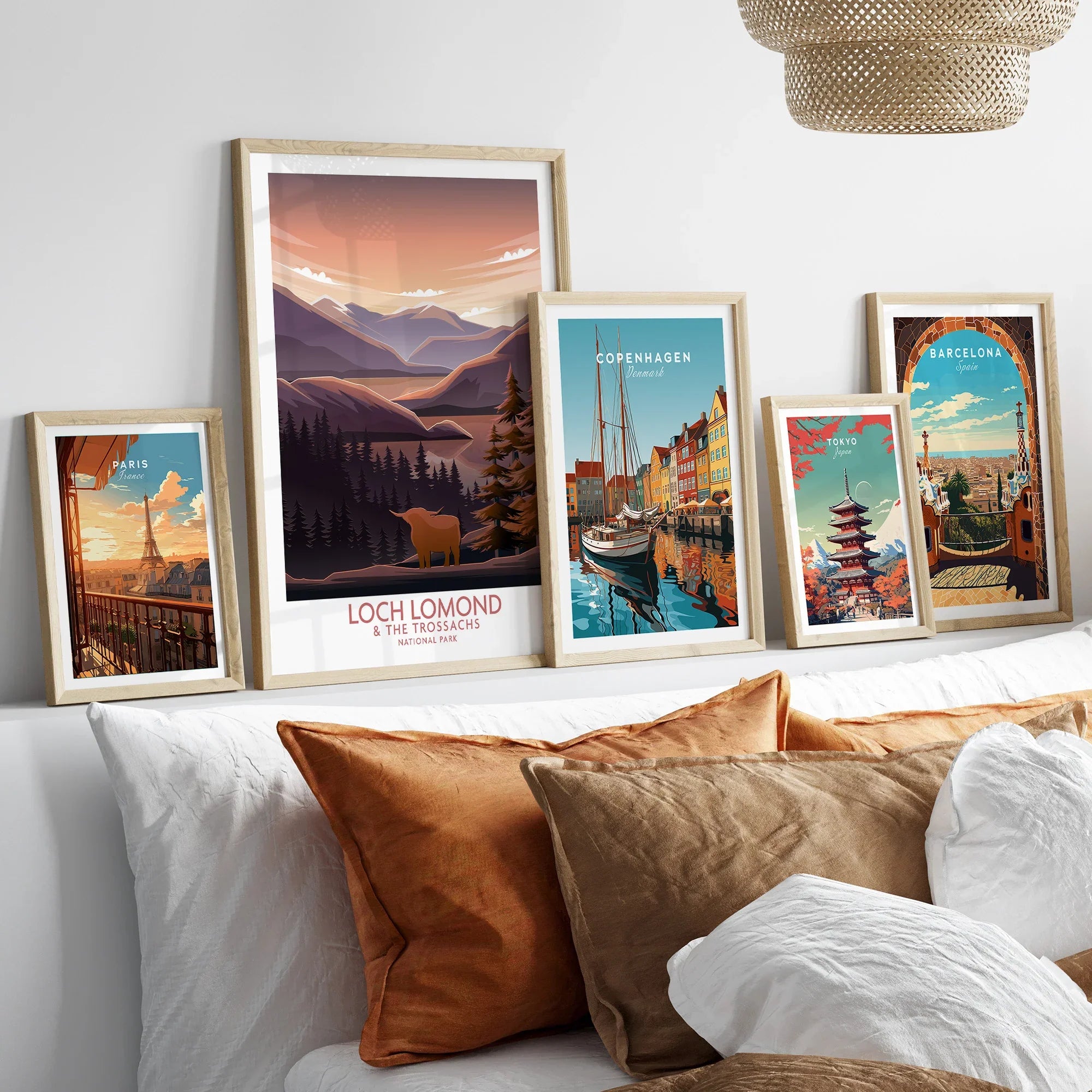 Framed travel art prints of Paris, Loch Lomond, Copenhagen, Tokyo, and Barcelona above bed