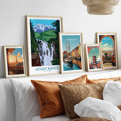 Set of five framed travel art prints above bed, featuring Paris, Mount Rainier, Copenhagen, Tokyo, Barcelona.